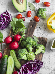 Fresh vegetables - broccoli, avocado, sweet peppers, cucumbers, tomatoes, radish on light background, top view. Flat lay