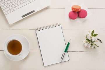 Office table, flowers, and macarons with cup of tea