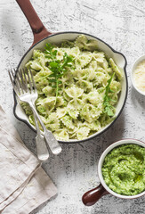 Vegetarian pasta farfalle with broccoli pesto in a cast iron skillet on the light table, top view