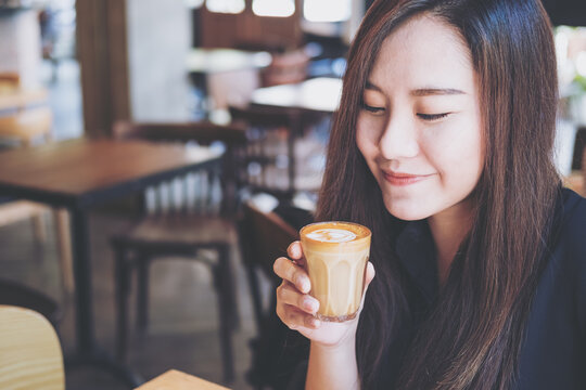 A beautiful Asian woman holding and drinking hot coffee with feeling good in vintage cafe