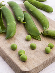Freschi piselli dell'orto su tagliere di legno pronti da cucinare