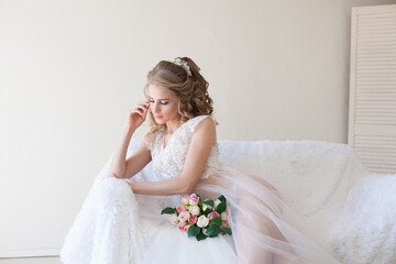 beautiful bride sitting on a white couch in lingerie