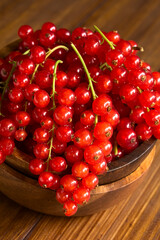 Rohe reife rote Johannisbeeren in Holzschüssel, fotografiert auf dunklem Holz mit natürlichem Licht (Selektiver Fokus, Fokus auf die vorderen Johannisbeeren)