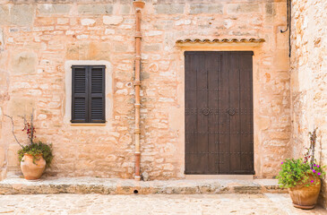 Fototapeta na wymiar Front Ansicht Haus Mediterran mit Holz Tür Braun Fensterläden und Stein Mauer rustikal