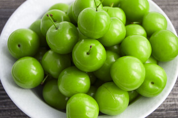 Green sour plums in the plate, plum pictures on the white ground,
Quality and natural life-giving green sour plums

