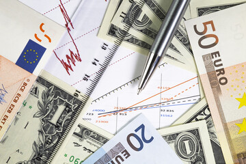 Concept of world stock market trading. Chart with  prices.one us dollar bills and euro fifty and twenty bills on the graph. . Ball pen, ruler  on the diagram. Macro image. 