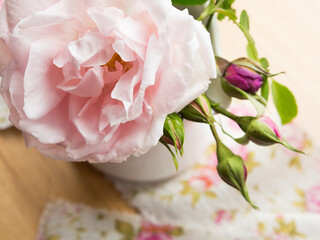 Rose and rose buds in a jug on a table with a rose ribbon