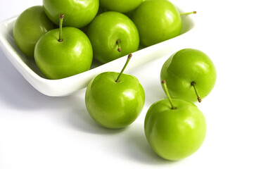 Green sour plums in the plate, plum pictures on the white ground,
Quality and natural life-giving green sour plums

