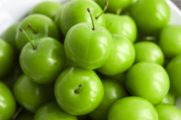Green sour plums in the plate, plum pictures on the white ground,
Quality and natural life-giving green sour plums

