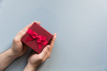 Flatlay holidays red giftbox present in man hands on the pastel blue background for father's day, christmas, birthday party