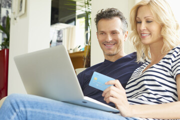 Fototapeta na wymiar Buying online. Shot of a happy mature couple buying online with their credit card at home. 