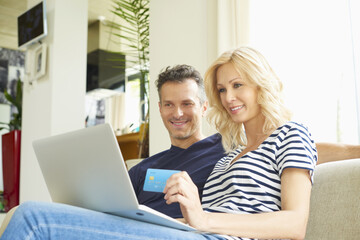 Buying online. Shot of a happy mature couple buying online with their credit card at home. 