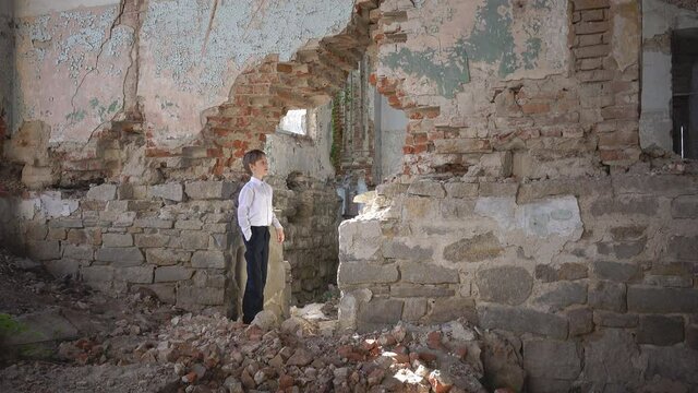 Confused boy, he alone in a ruined building, lost, fear, loneliness, threat, looks around and studies