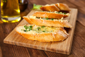 Tasty bread with garlic, cheese and herbs on kitchen table, close up