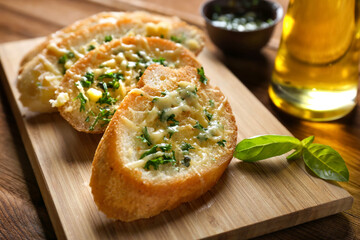 Tasty bread with garlic, cheese and herbs on kitchen table, close up