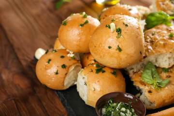 Tasty bakery products with garlic and herbs on kitchen table, close up view