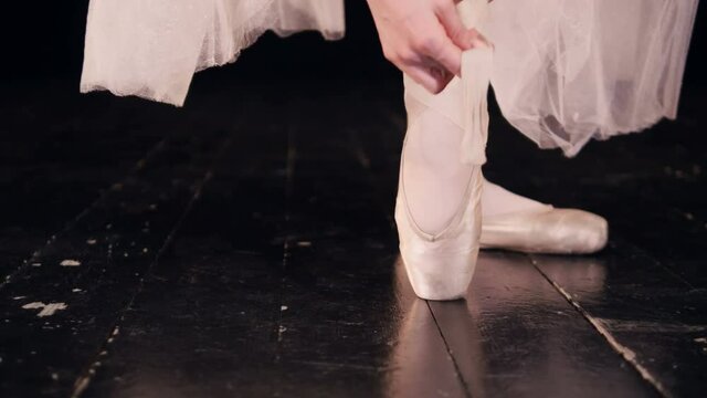 Female dancer putting on her ballet shoes