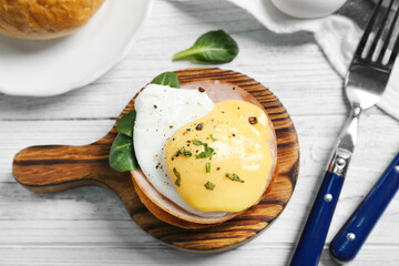 Tasty egg Benedict on wooden board