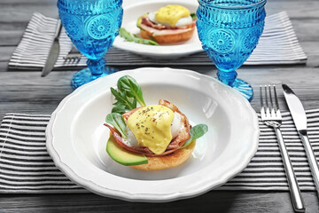 Tasty egg Benedict with cutlery on table