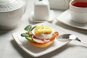 Tasty egg Benedict with fork on plate, closeup