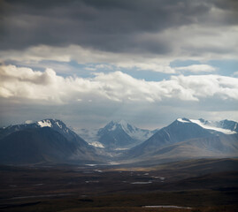 Altai Ukok the sunset over the mountains in cloudy cold weather. Wild remote places, no one around. Rain clouds over the mountains