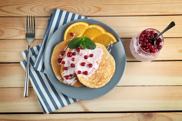Tasty yogurt pancakes with orange slices and berries on table, top view