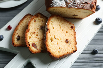 Delicious sliced yogurt cake with berries on white cutting board, closeup