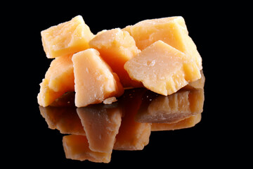 Parmesan cheese on a black glossy table with reflection. Parmesan cheese isolated on black background.