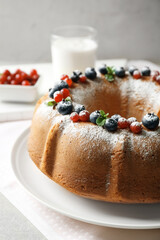 Plate with delicious yogurt cake and berries on blurred background