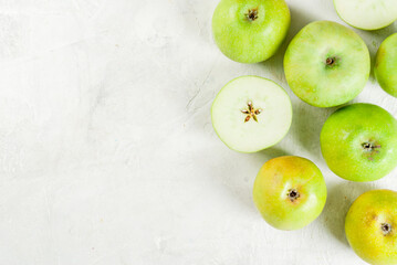 Green apples on a white stone table, whole and cut. Top view copy space