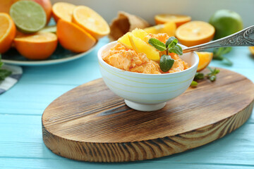 Delicious citrus ice cream with slices of orange and mint in bowl on cutting board