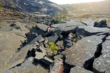 Young female tourist exploring surface of the Kilauea Iki volcano crater with crumbling lava rock in Volcanoes National Park in Big Island of Hawaii © MNStudio