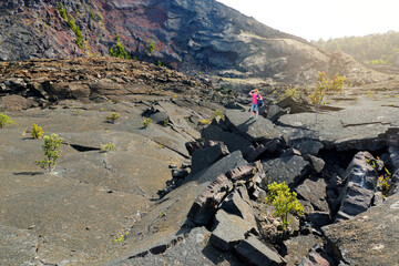 Young female tourist exploring surface of the Kilauea Iki volcano crater with crumbling lava rock in Volcanoes National Park in Big Island of Hawaii © MNStudio