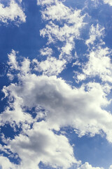 Cumulus clouds against the dark blue sky. Heavenly background. Vertical photography.