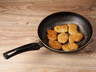 Chicken nuggets with sesame seeds on a frying pan