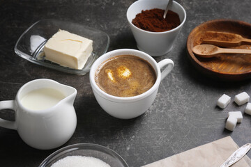 Composition with cup of coffee with butter on table