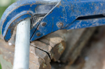 Old blue wrench unwind elbow from pipe, close up