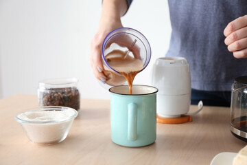 Woman pouring coffee with butter into mug, closeup