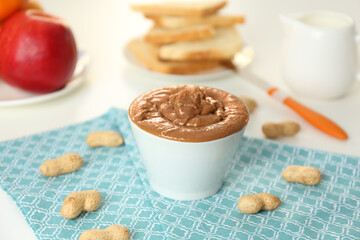 Delicious peanut butter in bowl on kitchen table, closeup