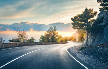 Mountain road. Landscape with rocks, sunny sky with clouds and beautiful asphalt road in the evening in summer. Vintage toning. Travel background. Highway in mountains. Transportation