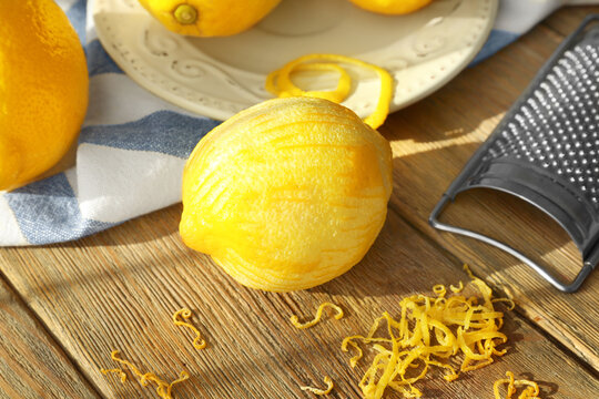 Peeled lemon, zest and grater on wooden table