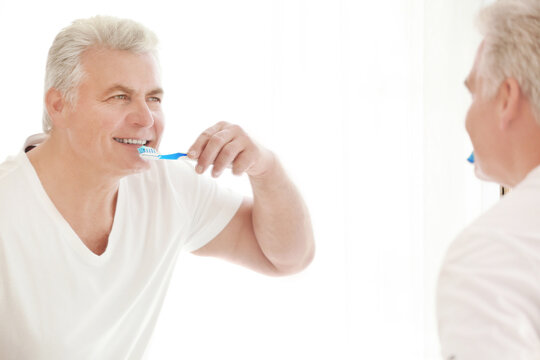 Senior man cleaning teeth at home