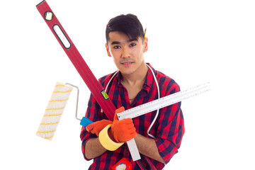 Young man in gloves holding level, roll and ruler 