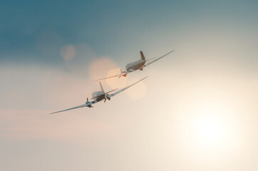 A pair of old turboprop aircraft in the sky at sunset.