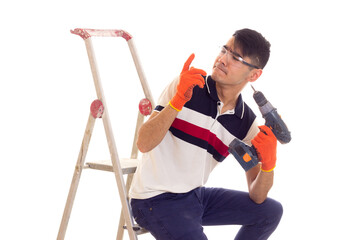 Young man holding electric screwdriver and sitting on ledder