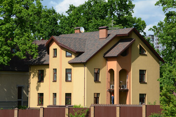 KIEV, UKRAINE - MAY 06, 2017: Roof Shingles - Roofing. Asphalt Roofing Shingles. Large modern house with large windows. Rain gutter. Chimney pipe. Long metal fence
