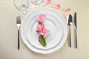 Beautiful festive table setting with floral decor on light tablecloth
