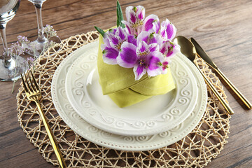 Beautiful festive table setting with floral decor on wooden surface