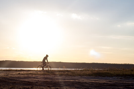 Alone rider on fixed gear road bike riding in the desert near river, hipster tourist bicycle rider pictures.