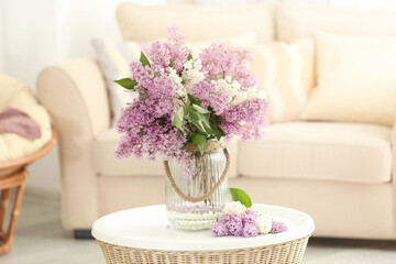 Glass vase with beautiful lilac flowers on table